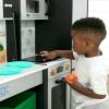 imageDelta Children Gourmet AllinOne Corner Play Kitchen  Toy Kitchen Playset with Safe ampamp Heatless Stove with Lights Oven Sink FridgeFreezer with Ice Maker and 20 Accessories NaturalWhiteGrey